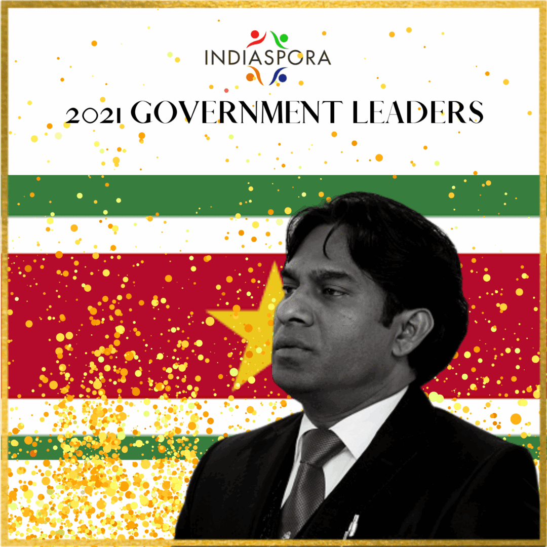 A man in a suit and tie standing next to an indian flag.