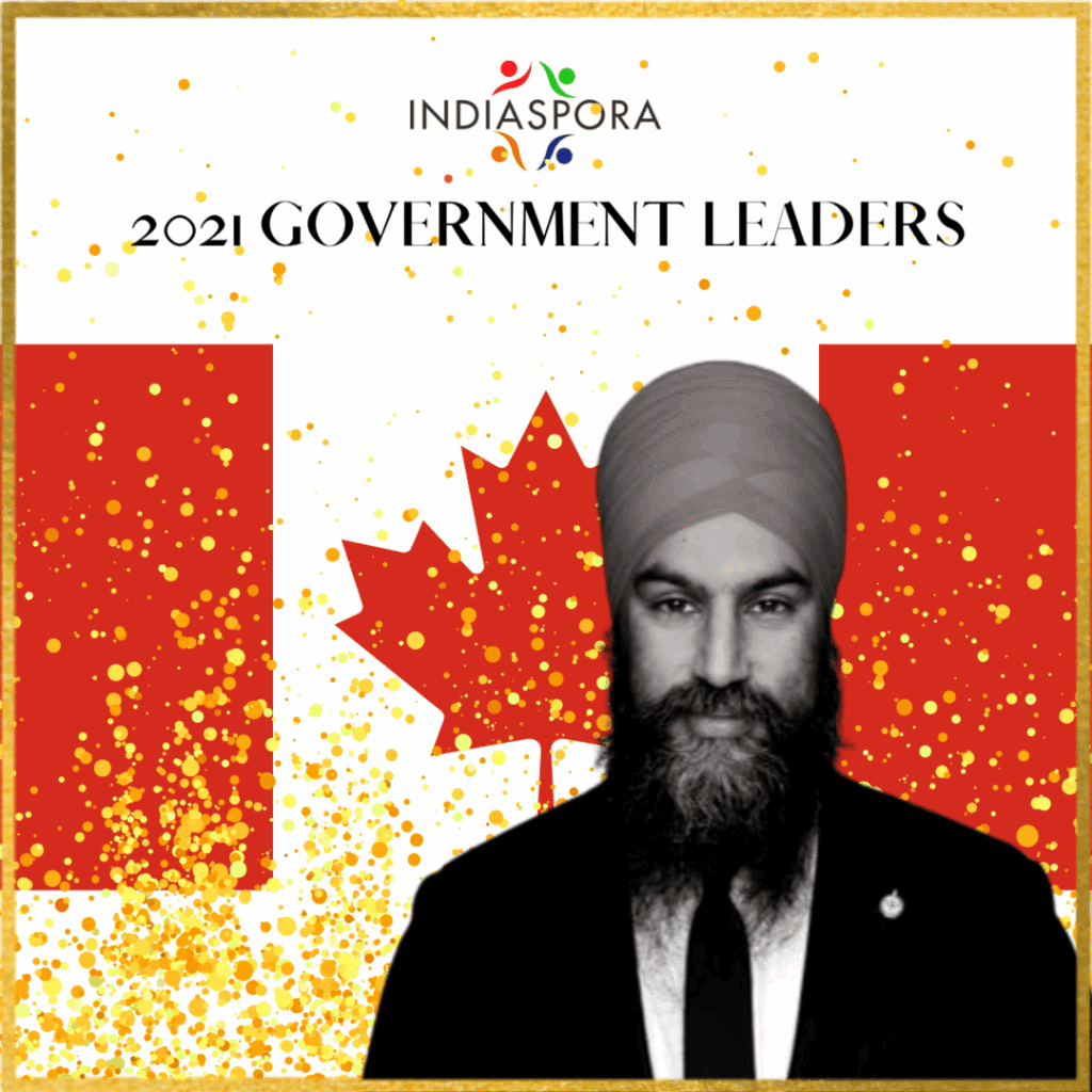A man in a suit and tie standing next to canadian flag.