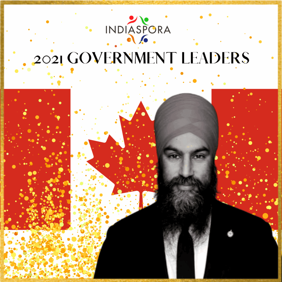 A man in a suit and tie standing next to canadian flag.