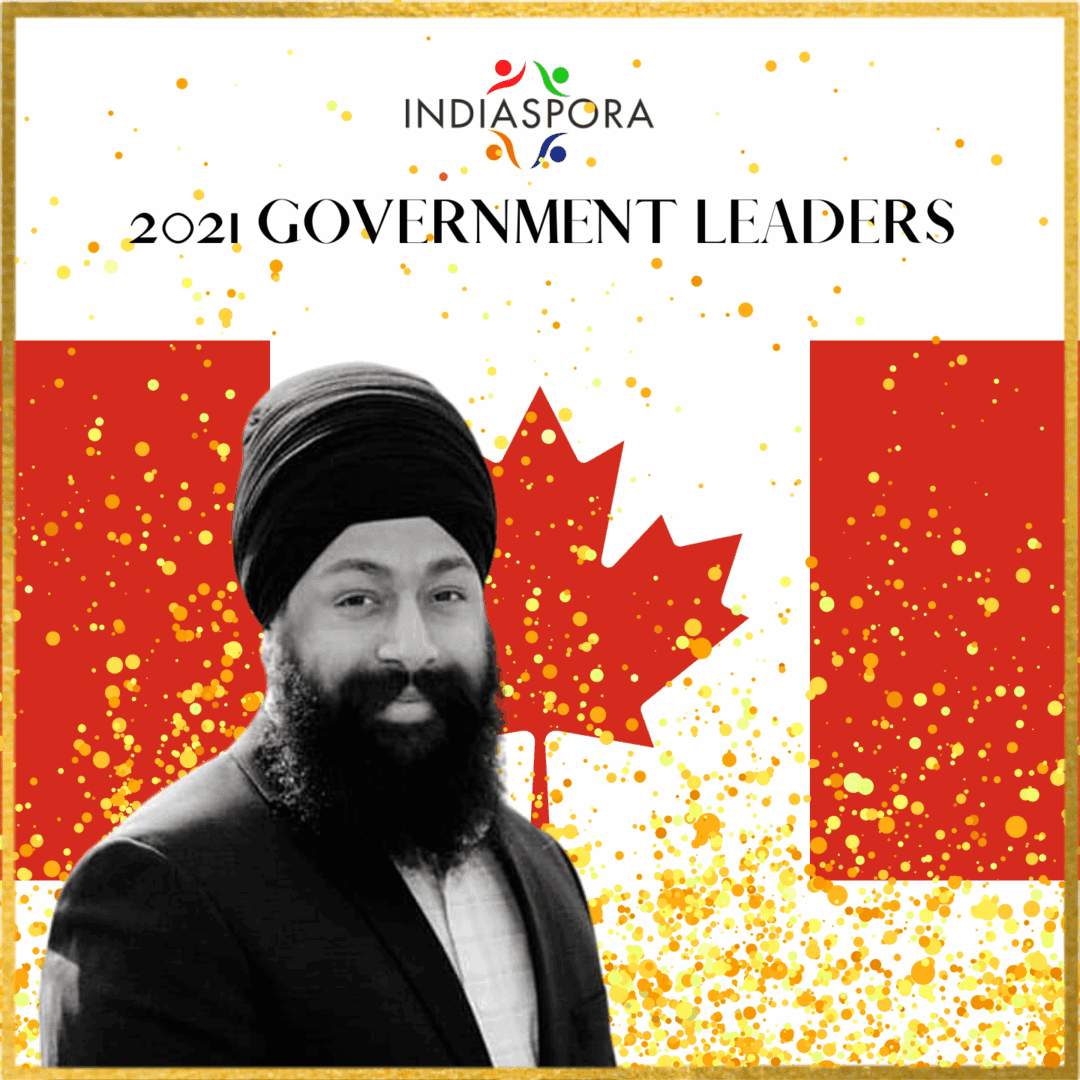 A man in black jacket and turban standing next to canadian flag.