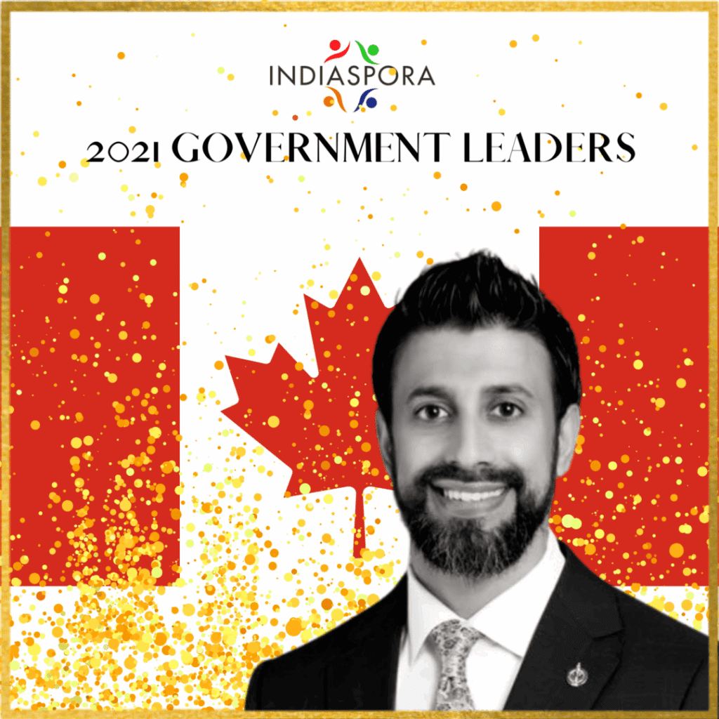 A man in a suit and tie standing next to the canadian flag.