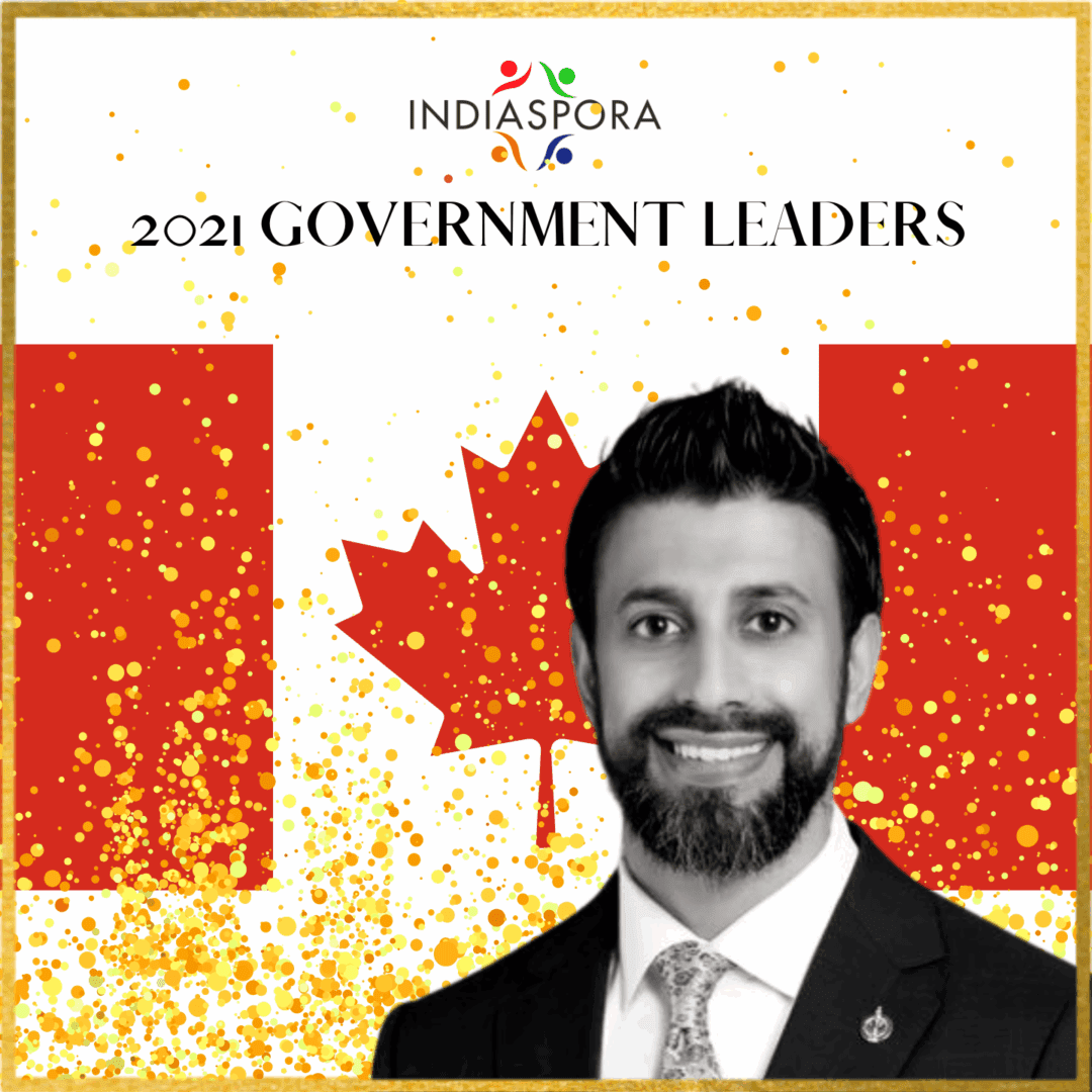 A man in a suit and tie standing next to the canadian flag.