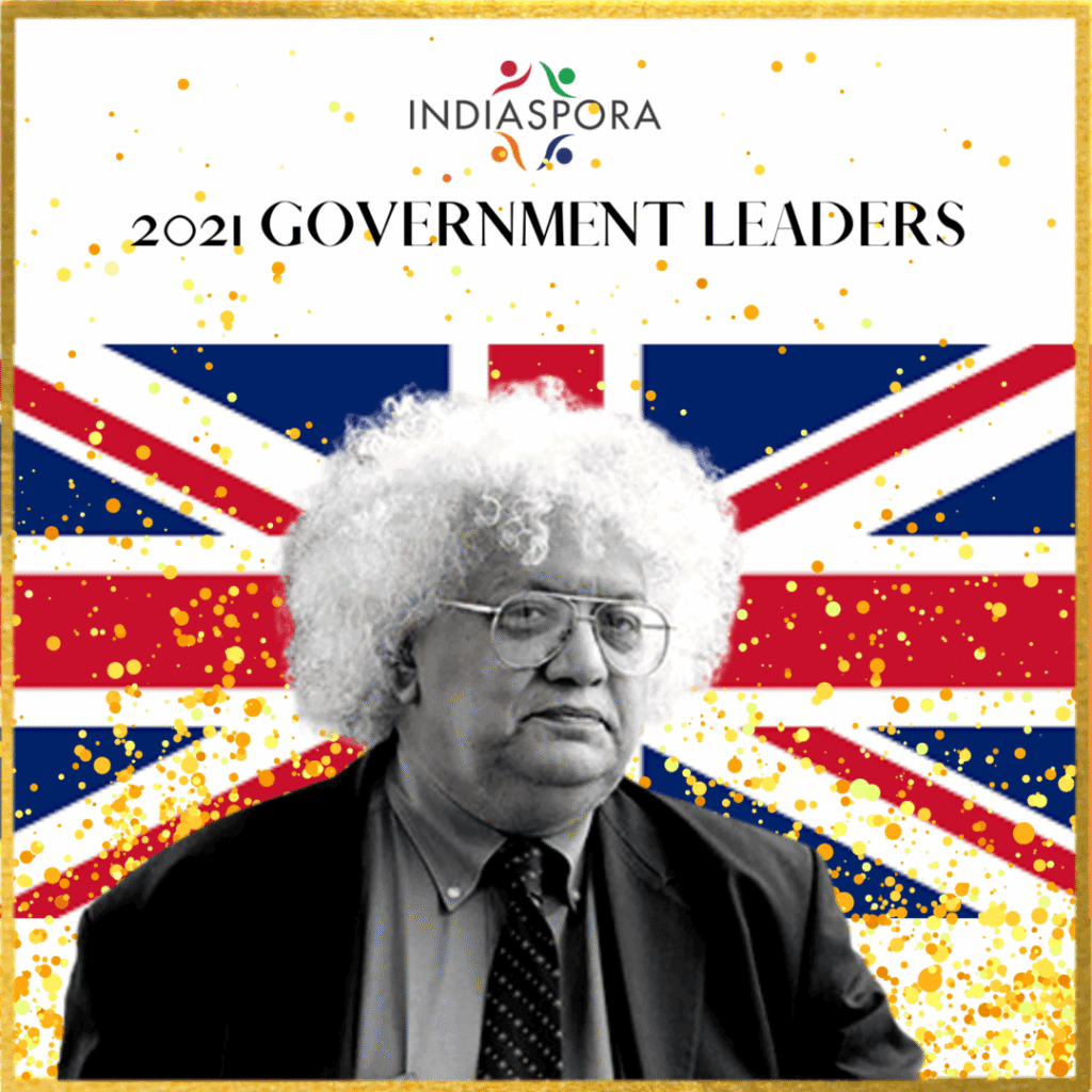 A person with curly hair and glasses in front of the british flag.