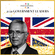 A man in glasses and suit standing next to the british flag.