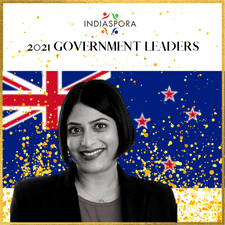 A woman standing in front of the flag of new zealand.