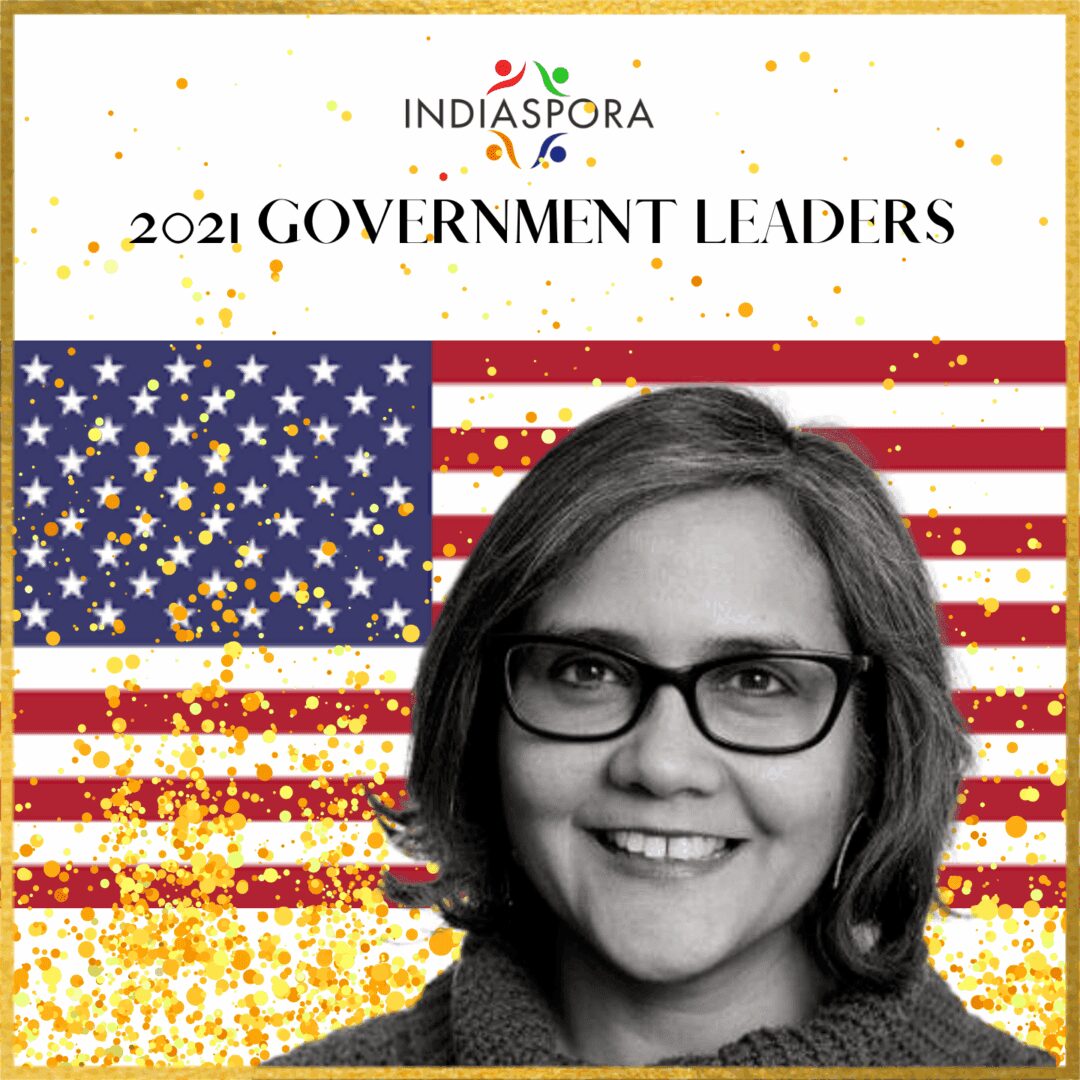 A woman with glasses standing in front of an american flag.