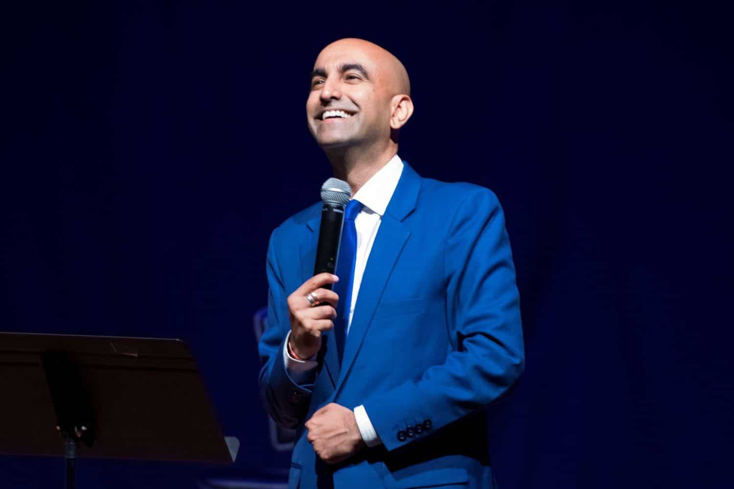 A man in blue jacket holding a microphone.