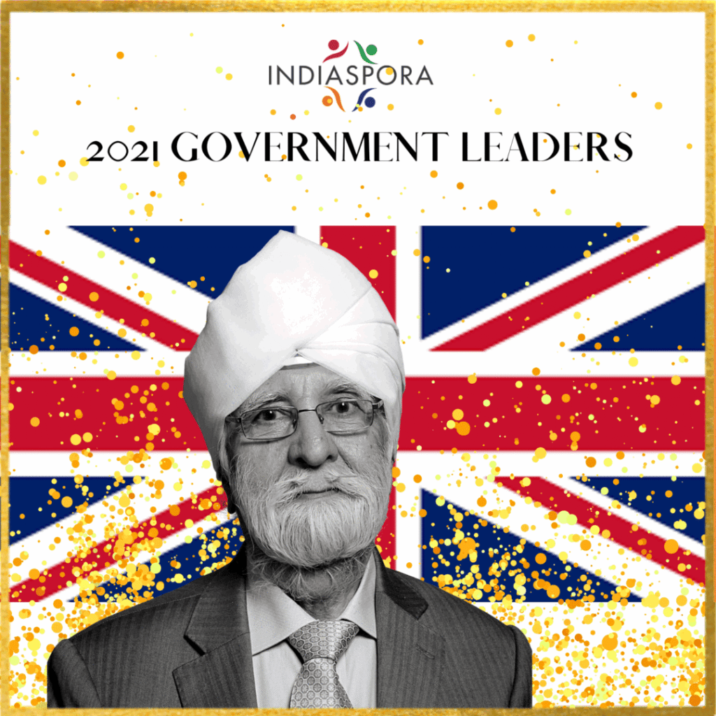A man with a turban and suit is in front of the british flag.