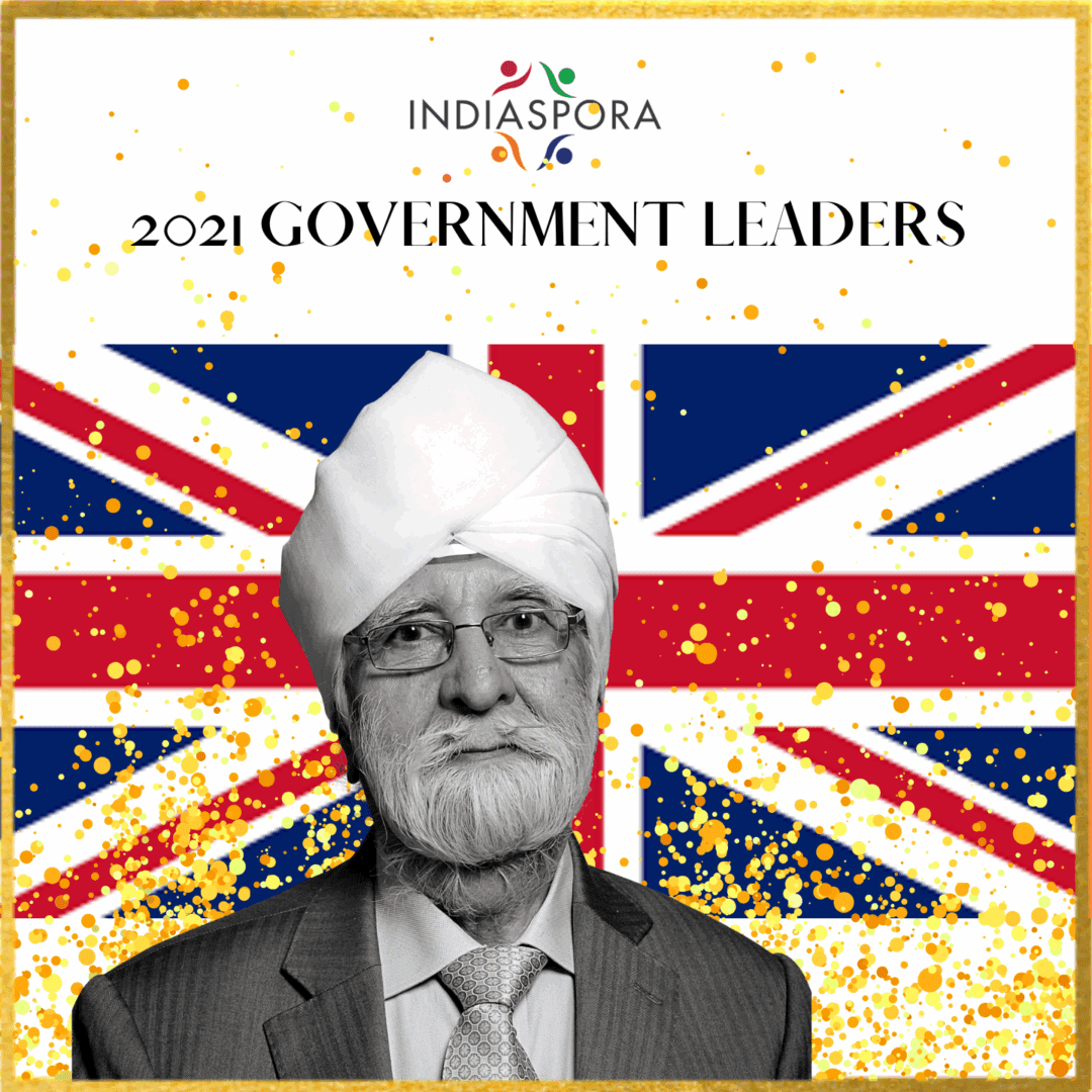 A man with a turban and suit is in front of the british flag.