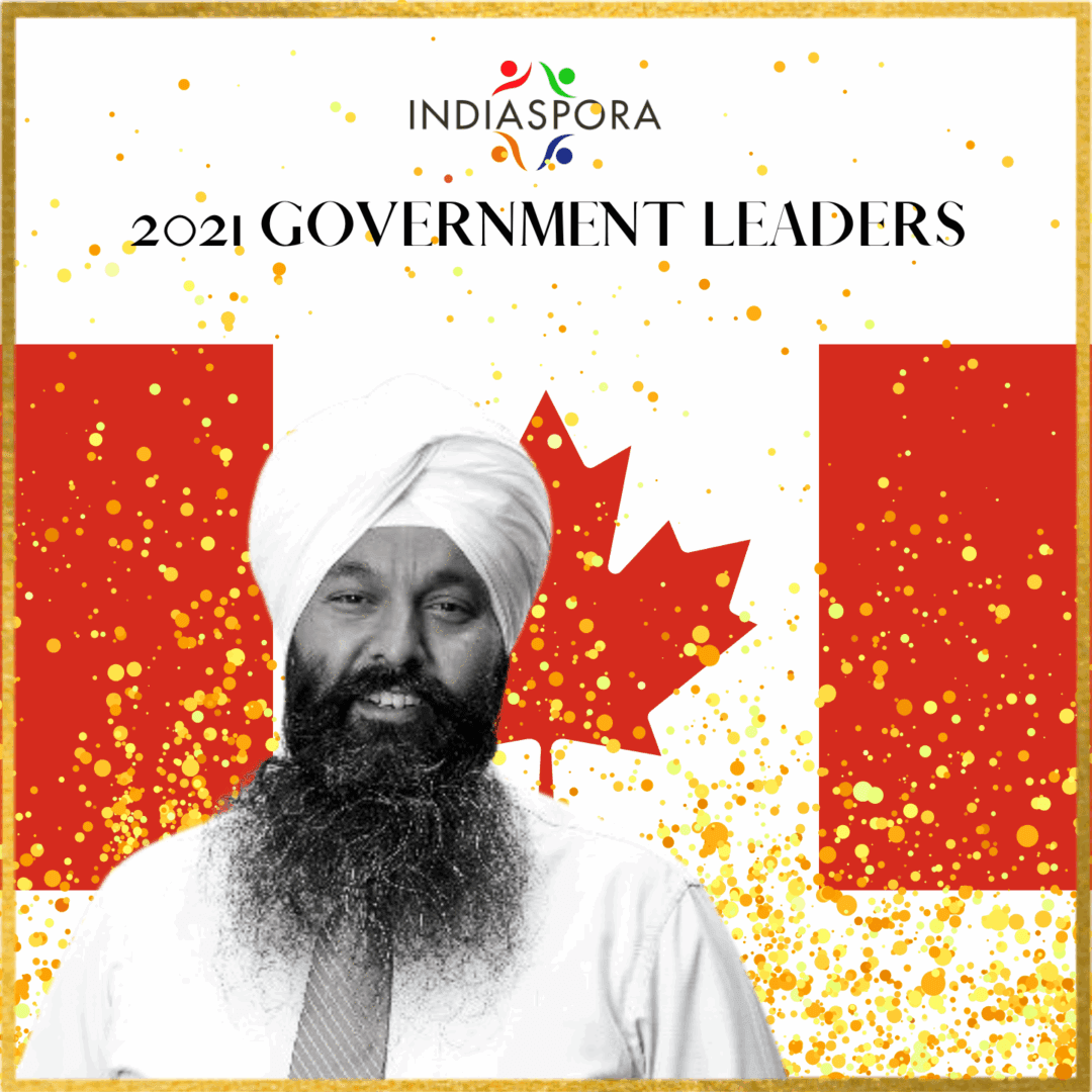 A man with a beard and turban standing in front of the canadian flag.