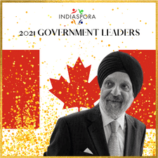 A man in a suit and tie standing next to a canadian flag.
