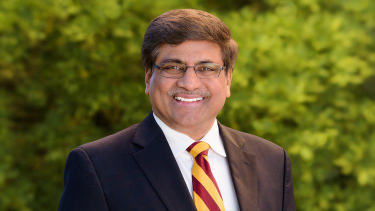A man in a suit and tie smiling for the camera.
