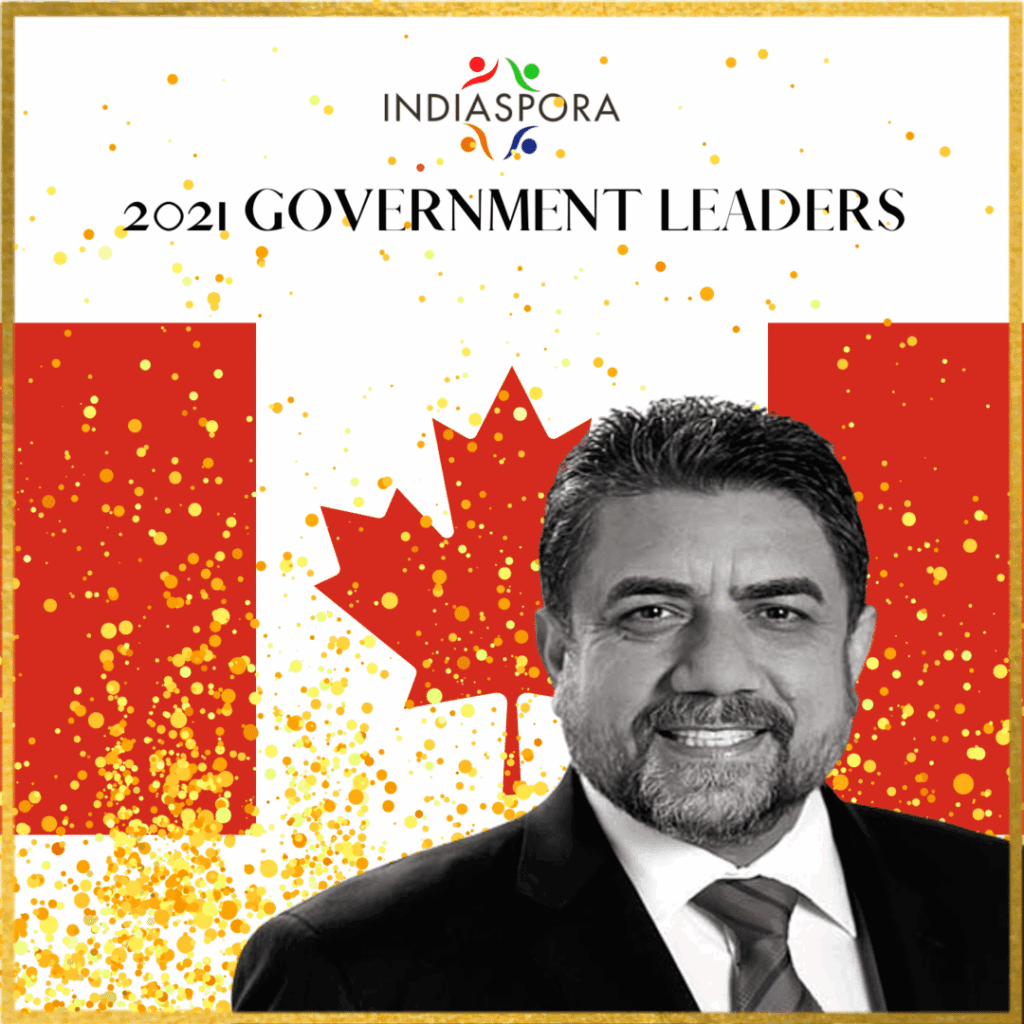 A man in a suit and tie standing next to the canadian flag.