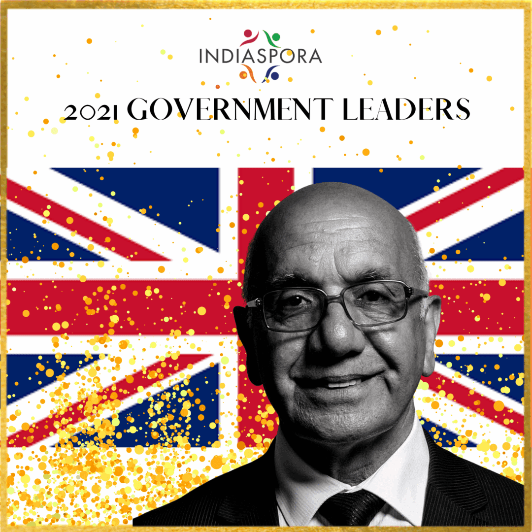A man in glasses and suit standing next to the british flag.