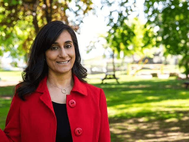 A woman in red jacket smiling for the camera.