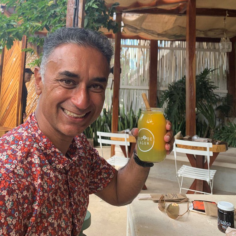 A man holding up an orange juice in his hand.